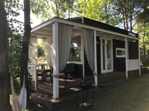 a small cabin with a porch and curtains at Domki nad morzem Sasino Mojo Miodno Checz in Sasino