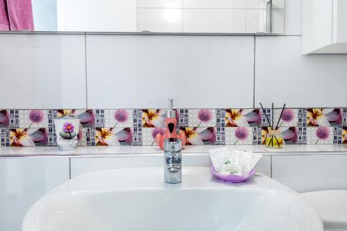 a bathroom with a sink and flowers on the wall at Lovely Acapulco Playa de Las Americas in Playa de las Americas