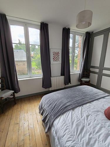 a bedroom with a bed and two windows at Maison en briques au 10 in Lamberville