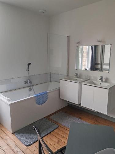 a white bathroom with two sinks and a mirror at Maison en briques au 10 in Lamberville
