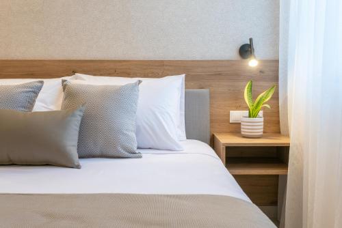 a bed with white pillows and a plant on a table at Alysos Luxurious Apartments in Mirina
