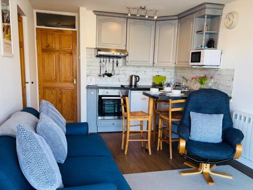 a living room with a blue couch and a kitchen at Georgina Portview- Pet Free-Allergy Friendly in Porthmadog