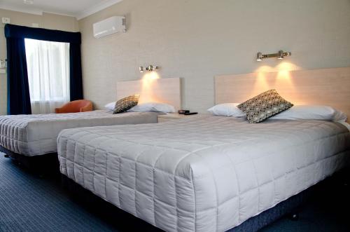 a hotel room with two beds and two lamps at Baybrook Motor Inn in Muswellbrook