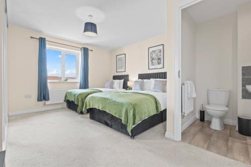 a bedroom with a large bed and a toilet at Stylish 4 Bedroom House in St Neots w Free Parking in Saint Neots