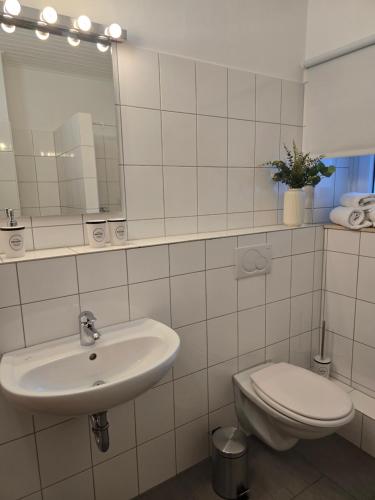 a white bathroom with a sink and a toilet at BOARDINGHOUSE PD25 ALTE FEUERWACHE I Unterkunft mit Einzel- und Doppelzimmer I 3min CityHospital I Monteure I Smart TV I Einzelbetten I Küche I Gemeinschaftsraum I Wasch I P in Ibbenbüren