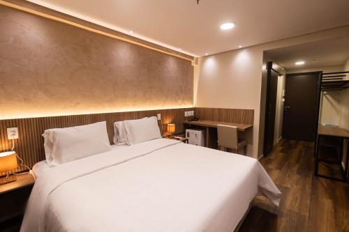 a bedroom with a large white bed and a desk at Arrey Gran Hotel in Teresina