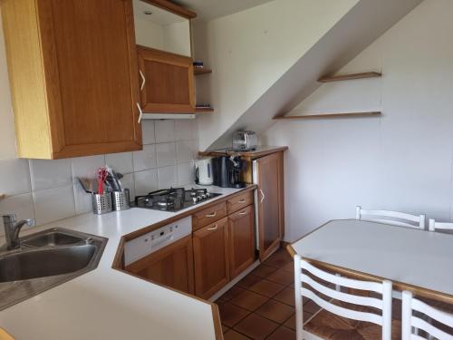 Elle comprend une petite cuisine avec des placards en bois et un évier. dans l'établissement Grande longère au port, à Perros-Guirec