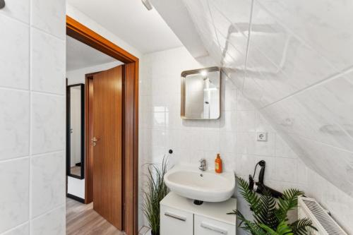 a white bathroom with a sink and a mirror at Larooms - Naumi#1 in Merseburg