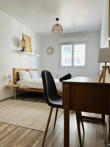 Cette chambre comprend un bureau et un lit en arrière-plan. dans l'établissement Appartement Le Renard - F2 parking calme, à Rouen