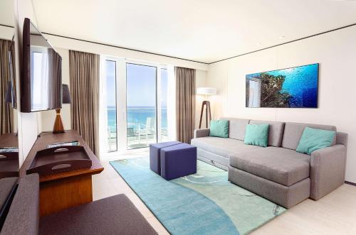 a living room with a couch and a large window at Sonesta Maho Beach All Inclusive Resort Casino & Spa in Maho Reef