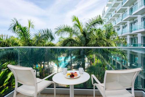 d'une table et de chaises sur un balcon avec des palmiers. dans l'établissement Sonesta Maho Beach All Inclusive Resort Casino & Spa, à Maho Reef