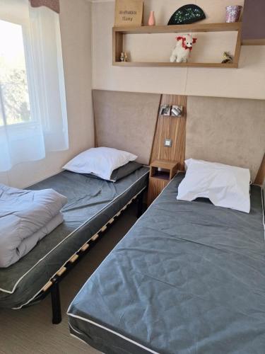deux lits jumeaux dans une chambre avec fenêtre dans l'établissement MOBIL HOME le CHOW-CHOW, à Valras-Plage