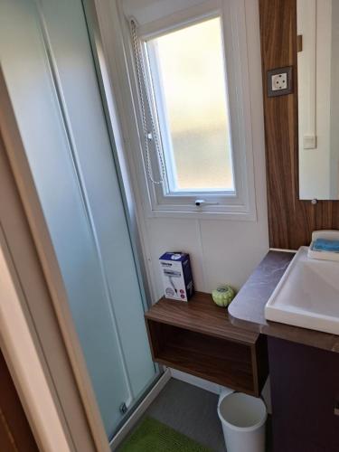 une salle de bain avec un lavabo et une fenêtre dans l'établissement MOBIL HOME le CHOW-CHOW, à Valras-Plage