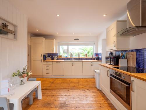 a kitchen with white cabinets and a wooden floor at The Bolthole in Kingsbridge