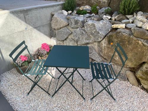 two chairs and a table in front of a rock wall at Neue helle Wohnung mit Bergblick am Eingang der Jungfrau Region und Berner Oberland in Aeschi bei Spiez