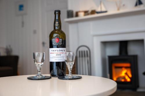 a bottle of wine sitting on a table with two glasses at The Bolthole in Kingsbridge