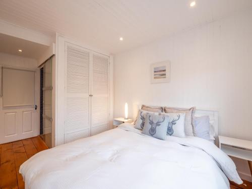 a white bedroom with a large white bed with blue pillows at The Bolthole in Kingsbridge