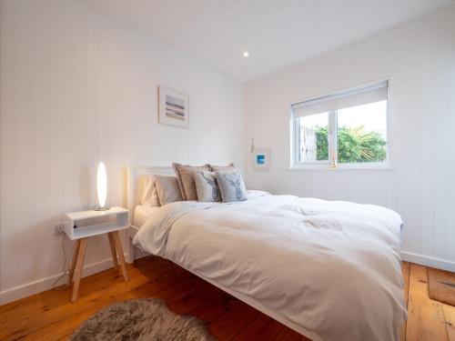 a white bedroom with a large bed and a window at The Bolthole in Kingsbridge