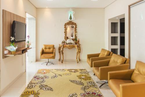 a living room with chairs and a tv and a mirror at Hotel Nacional Inn Araçatuba in Araçatuba