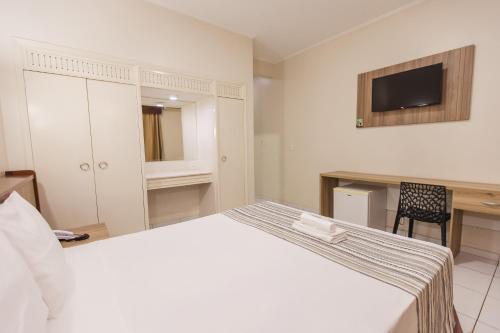 a bedroom with a bed and a desk and a television at Hotel Nacional Inn Araçatuba in Araçatuba