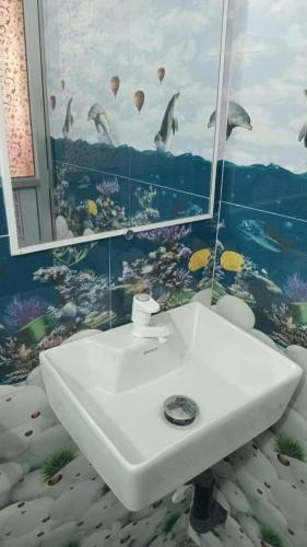 a bathroom with a sink and a painting of birds at Una Star Guest House in Trincomalee