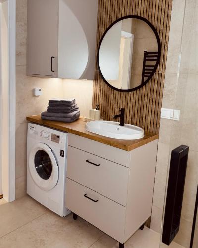 a bathroom with a sink and a washing machine at Apartamenty Cisza Natury - BRYZA in Augustów