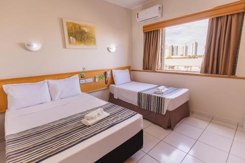 a hotel room with two beds and a window at Hotel Nacional Inn Araçatuba in Araçatuba