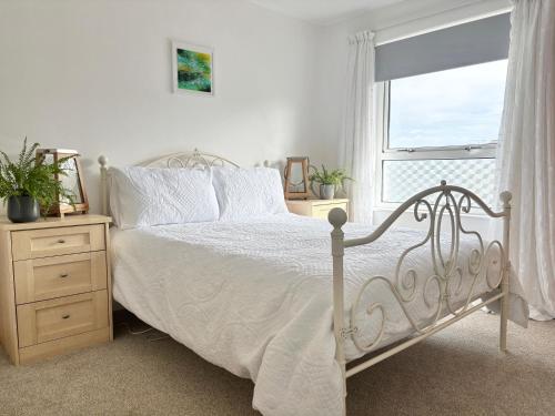 a bedroom with a white bed and a window at Falmouth Oasis with sub-tropical garden & parking in Falmouth