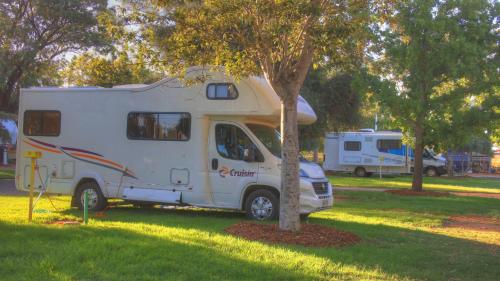 a white caravan parked next to a tree at West View Caravanpark in Dubbo
