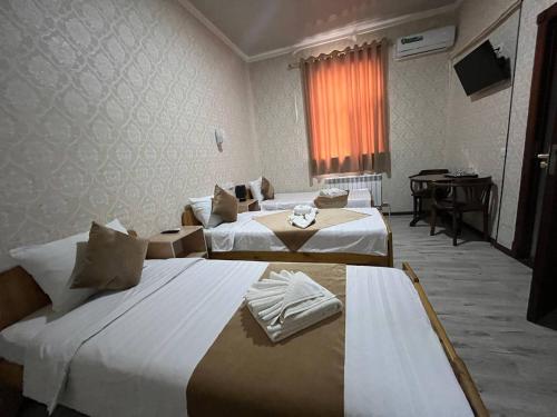 ein Hotelzimmer mit 2 Betten und einem Klavier in der Unterkunft Polvon Ota Hotel in Xiva