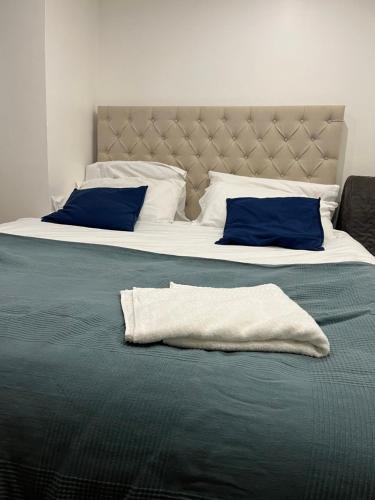 two beds with blue pillows and a blanket at A Cosy Ground Floor Flat in London