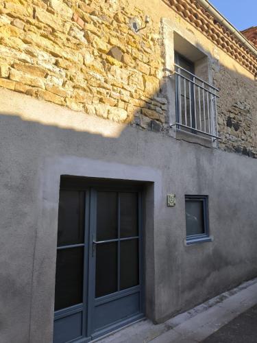 a gray building with a door and a window at Ma douce Fenière in Saint-Rémy-de-Chargnat