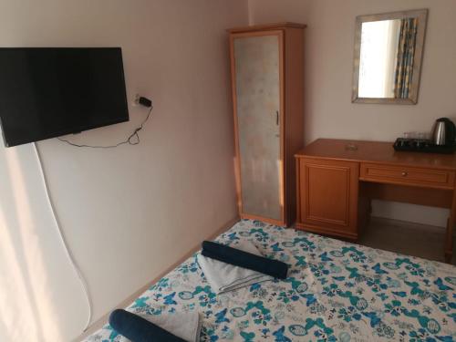 a room with a bed with a television on the wall at Özmert otel in Antalya