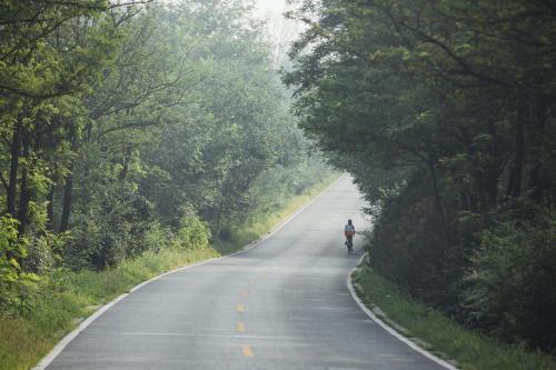 a person riding a bike down a road at The Long Circle House in Yanqing