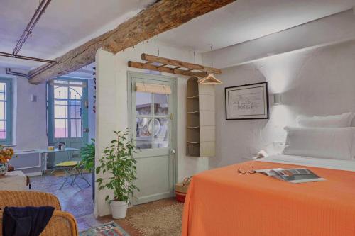 - une chambre avec un lit doté d'une couverture orange et d'une fenêtre dans l'établissement L'Atelier, à Béziers