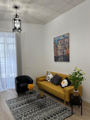 a living room with a yellow couch and a black chair at Apartamento Vinoble Jerez in Jerez de la Frontera