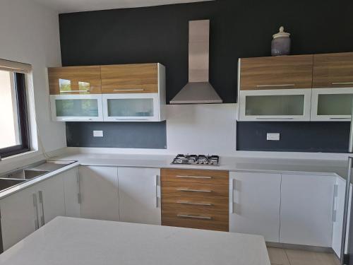 a kitchen with white cabinets and a stove at villazur in Flic-en-Flac