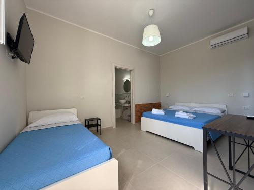a bedroom with two beds and a table and a television at Villa Paestum in Paestum