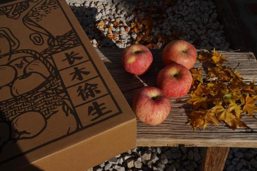 three apples on a wooden table next to a box at The Long Circle House in Yanqing