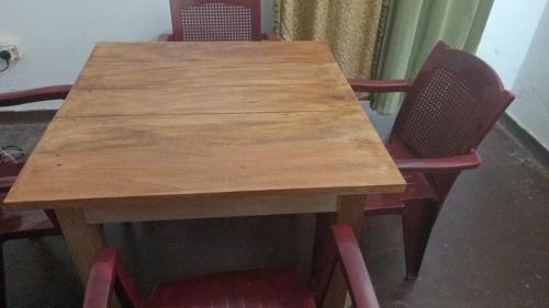 a wooden table with two red chairs around it at Una Star Guest House in Trincomalee