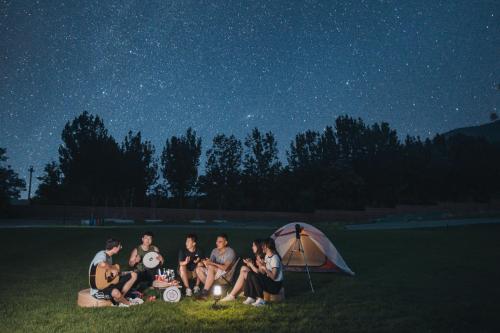 a group of people sitting on the grass under a tent at The Long Circle House in Yanqing