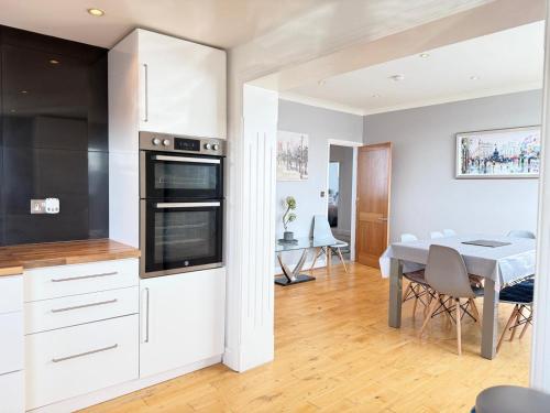 a kitchen and dining room with white cabinets and a table at Palm Bay Residency in Cliftonville