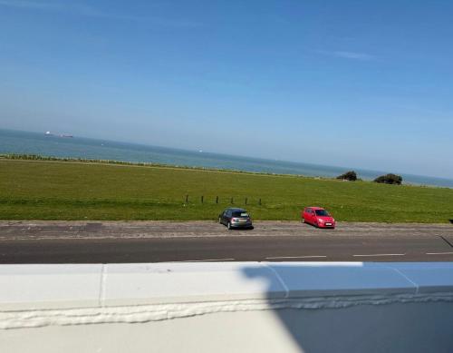 two cars driving on a road next to a field at Palm Bay Residency in Cliftonville