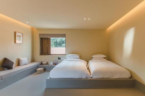 two beds in a room with a bench and a window at The Long Circle House in Yanqing