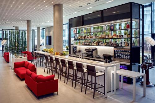 a bar in a restaurant with red chairs and a counter at Pullman Paris Roissy Cdg Airport in Roissy-en-France