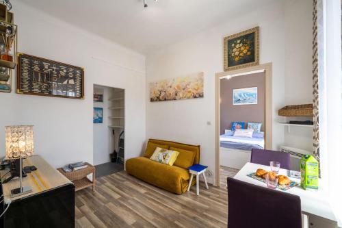 a living room with a yellow couch and a bed at Les voiles des Régates, à 5 minutes du centre à pied, 15 minutes de la mer in Cannes
