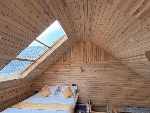 a bed in a wooden room with a window at Apple Land by Naavagat in Jibhi