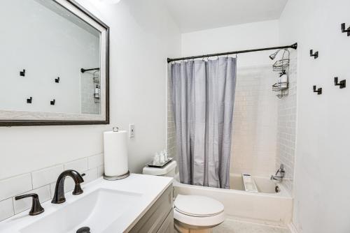 a white bathroom with a toilet and a sink at 1 Mi to Tulsa Arts District Updated Home with Deck! in Tulsa