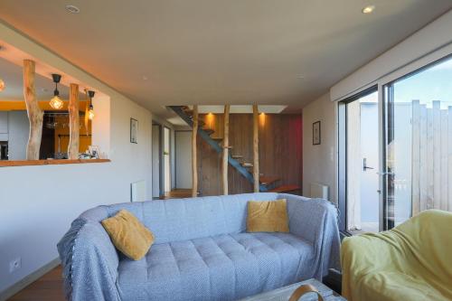 a living room with a blue couch and a staircase at Maison de charme vue mer et jacuzzy in Langueux
