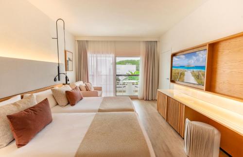 a hotel room with a bed and a television at Grand Palladium Select Palace Ibiza - All Inclusive in Playa d'en Bossa